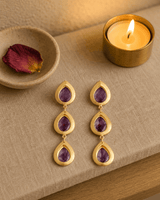 Amethyst teardrop earrings displayed on a lifestyle shelf, featuring purple gemstone drops in silver settings