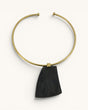 Ankole horn pendant brass choker necklace flat lay, dark trapezoidal horn piece on open brass collar, white background