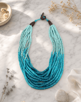 Aqua ombre coconut bead necklace displayed on white marble surface