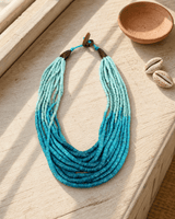 Aqua ombre coconut bead necklace displayed on sunlit outdoor window ledge