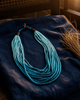 Aqua ombre beaded coconut necklace with vibrant rim lighting highlighting blue-to-teal gradient wood beads