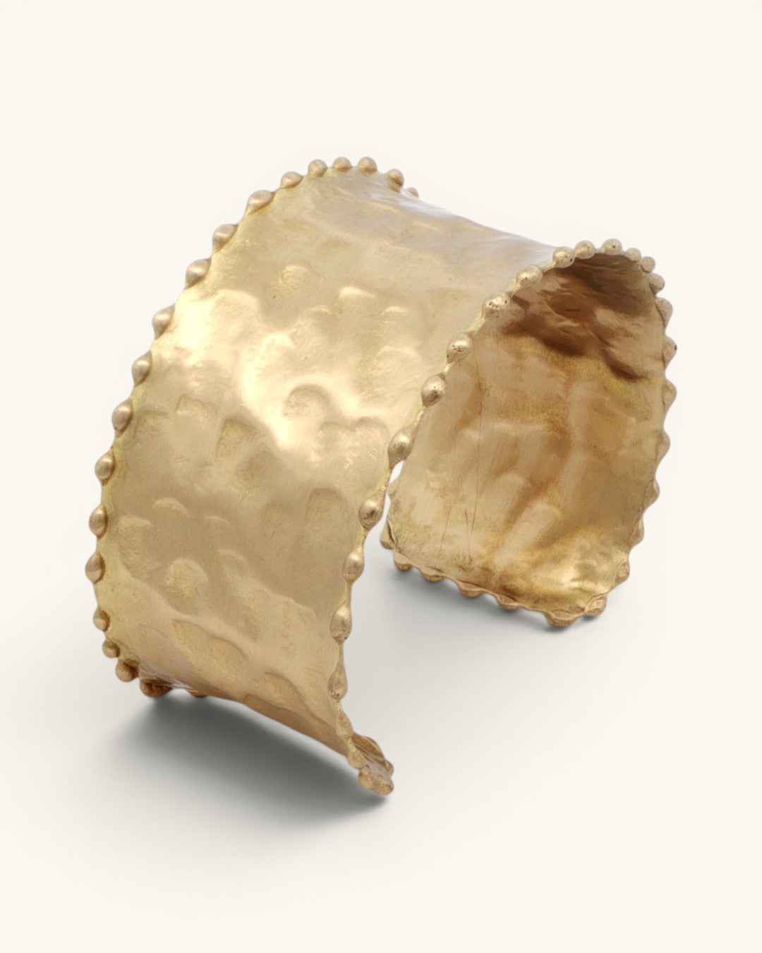 Beaded edge hand-hammered brass cuff bracelet shown from a low side angle, highlighting the open cuff gap and beaded trim