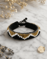 Black and gold beaded Kenyan bracelet displayed on white marble surface