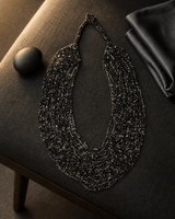 Black and grey multi-strand glass beaded necklace with dramatic rim lighting highlighting bead texture and layered strands