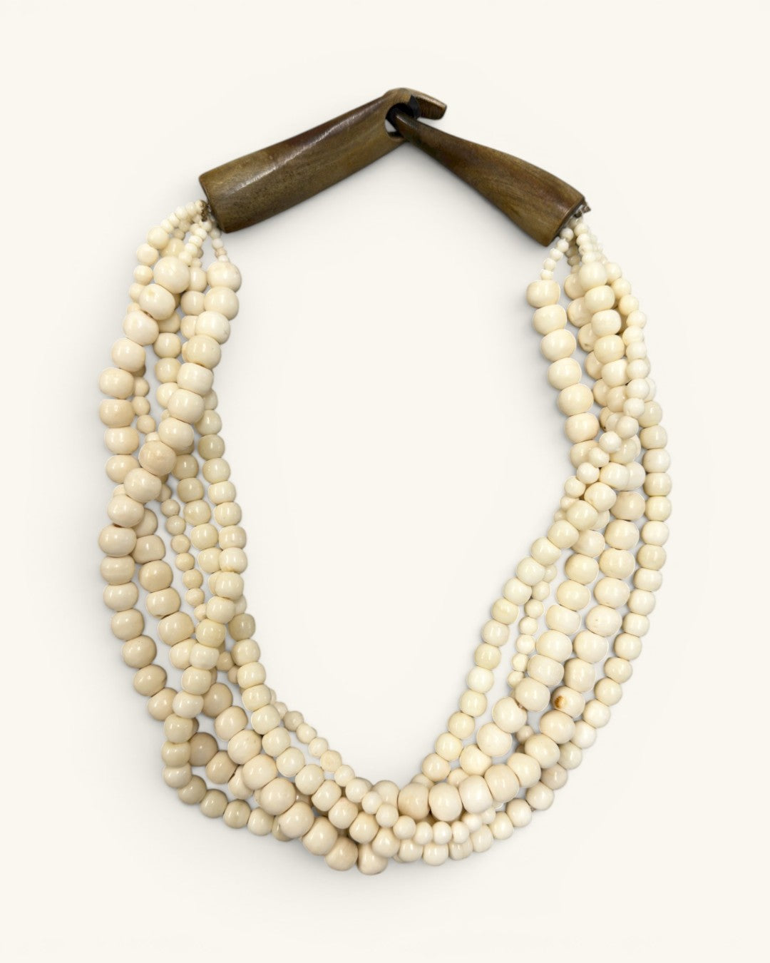 Indian bone bead 5-strand layered necklace on white background, angled flat lay showing bead texture and fastened horn closure