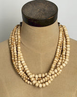 Five-strand Indian bone bead necklace draped on a burlap dress form, showing layered strand arrangement from front