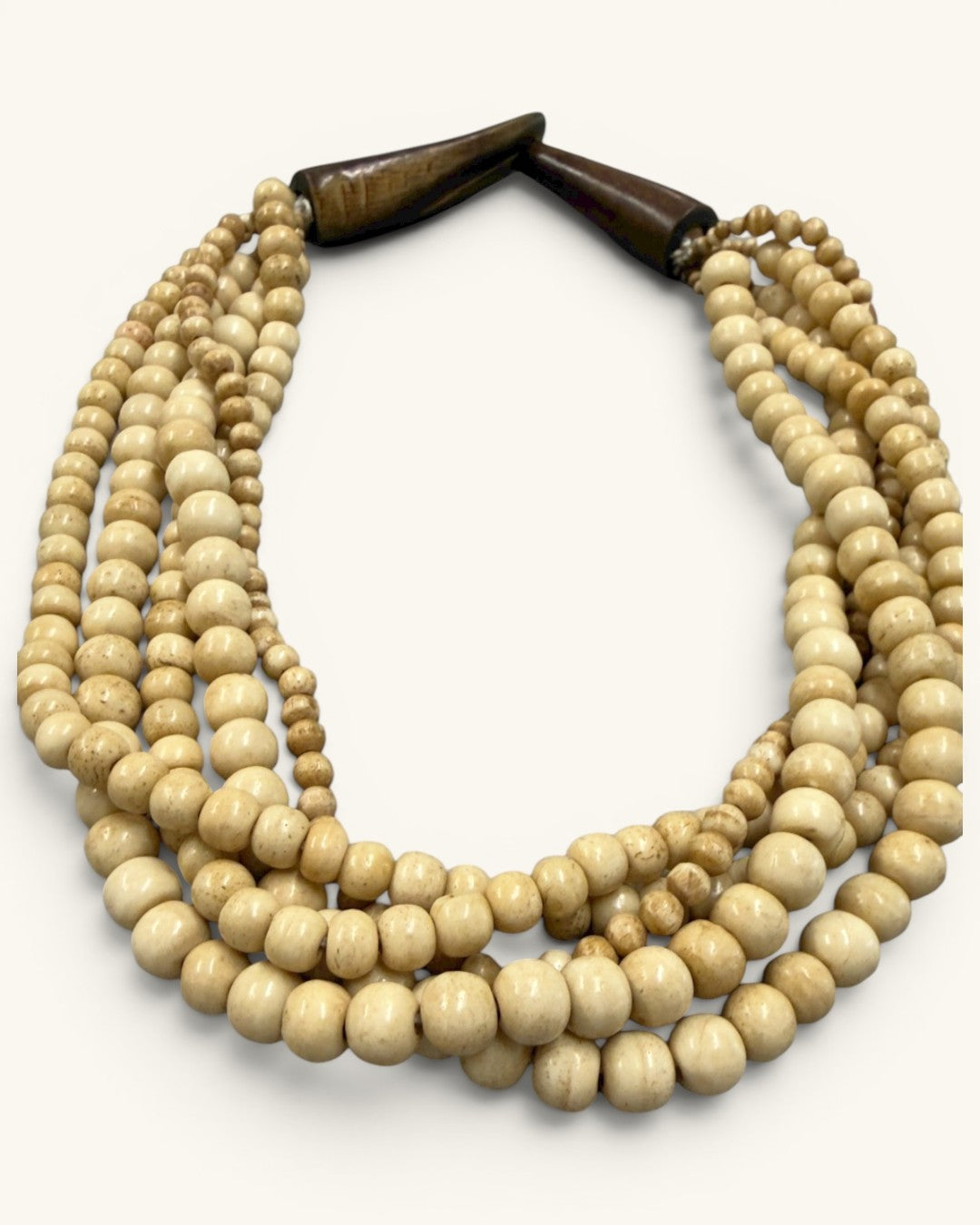 Angled close-up of five-strand bone bead necklace highlighting varied bead sizes and natural surface texture, horn closure visible