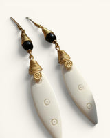 Close-up detail of both Kenyan artisan earrings showing brass coil caps, black beads, spiral motif, and carved bone pendants