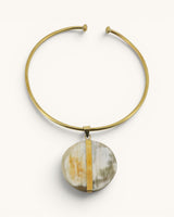 Brass collar choker necklace with round Ankole horn disc pendant and vertical brass bar accent, front view on white background