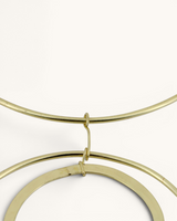 Close-up detail of the brass jump ring connection joining the double ring pendants to the collar necklace