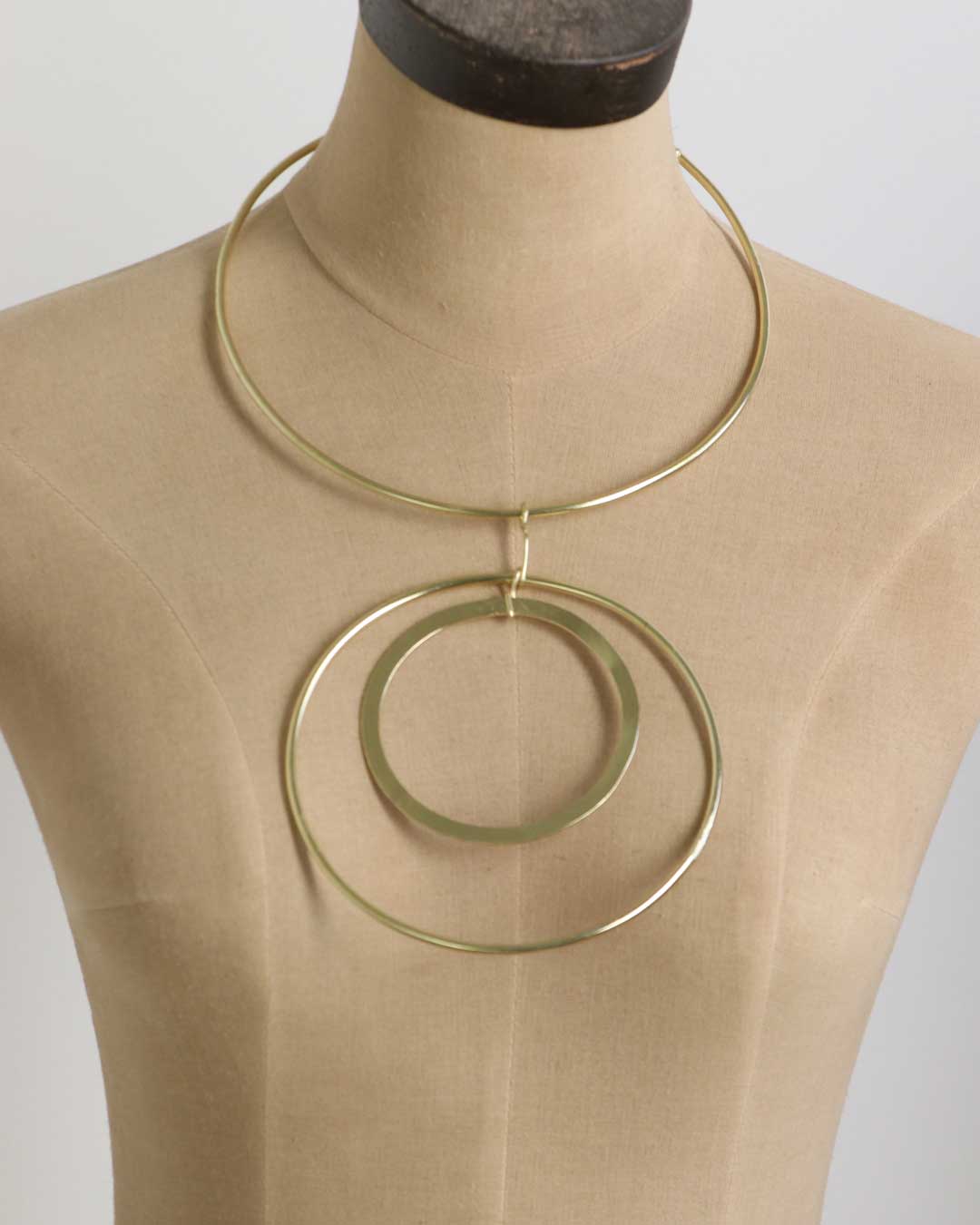 Brass collar necklace with nested double ring pendants displayed on a dress form, full front view