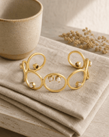 Brass cuff bracelet with opal and rose quartz stones displayed on a wooden lifestyle shelf