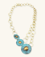 Hand-forged brass disc statement necklace full front view, three blue patina discs graduating in size on a double open-link brass chain