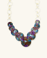 Close-up detail of hand-forged brass disc necklace showing hammer texture and purple blue patina finish