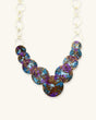 Close-up detail of hand-forged brass disc necklace showing hammer texture and purple blue patina finish