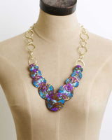 Front view of Indian hand-forged brass disc necklace with purple and blue patina against neutral background