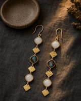 Brass drop earrings featuring oval labradorite and moonstone gemstones with warm rim lighting highlighting metallic details
