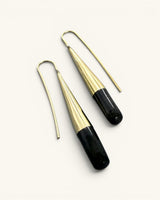 Tosha brass horn threader earrings angled flat on white background, close view of brass fluting and black horn drop texture