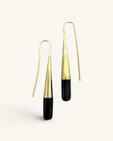 Tosha brass horn threader earrings on white background, front view of gold ribbed cones and black horn cylindrical drops
