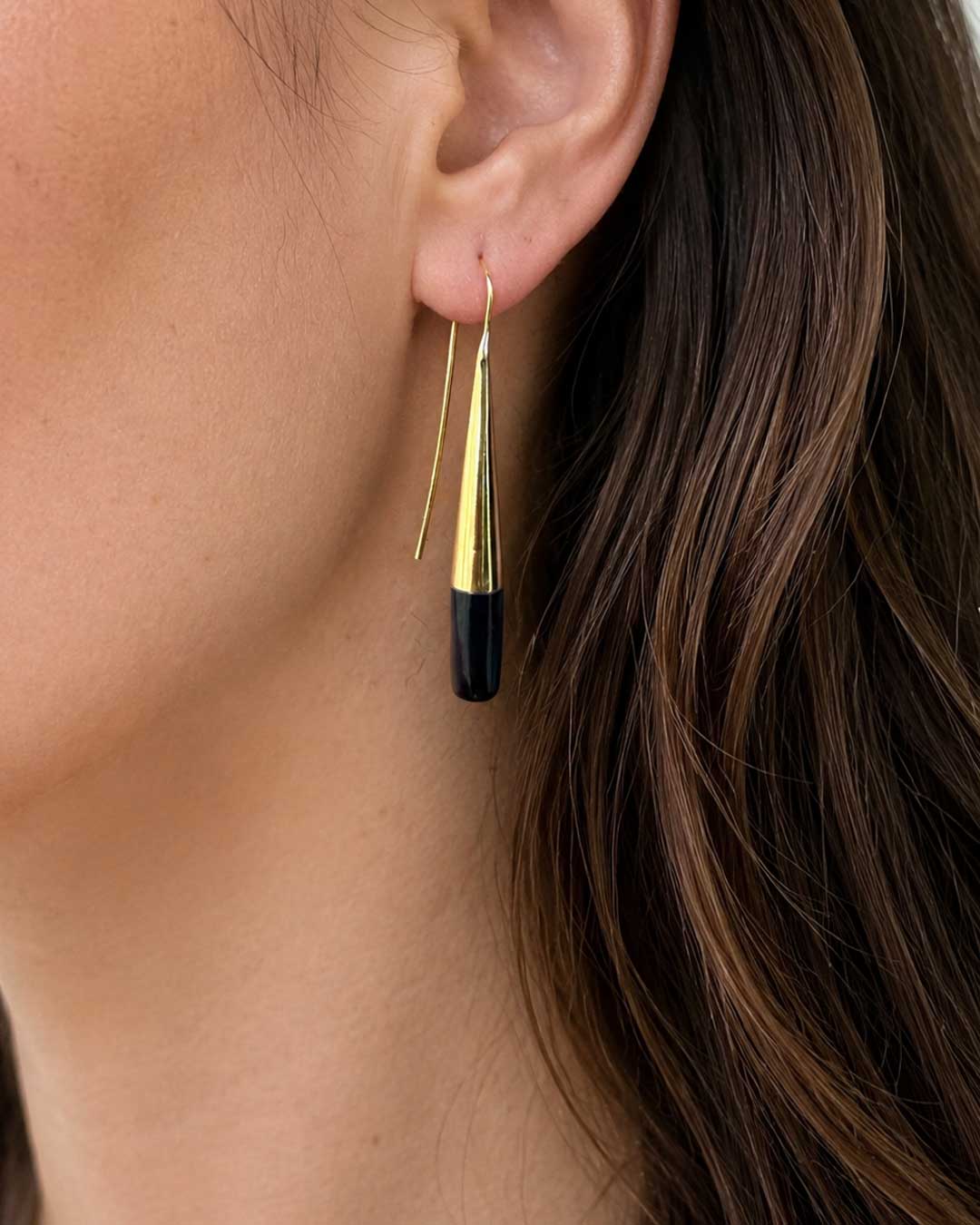 Tosha brass horn threader earring worn on model's ear, side profile showing gold cone and black horn drop against dark hair