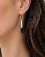 Tosha brass horn threader earring worn on model's ear, side profile showing gold cone and black horn drop against dark hair