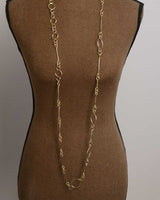 Brass link geometry long wrap necklace as single unlooped strand on dress form, showing full drop length to waist
