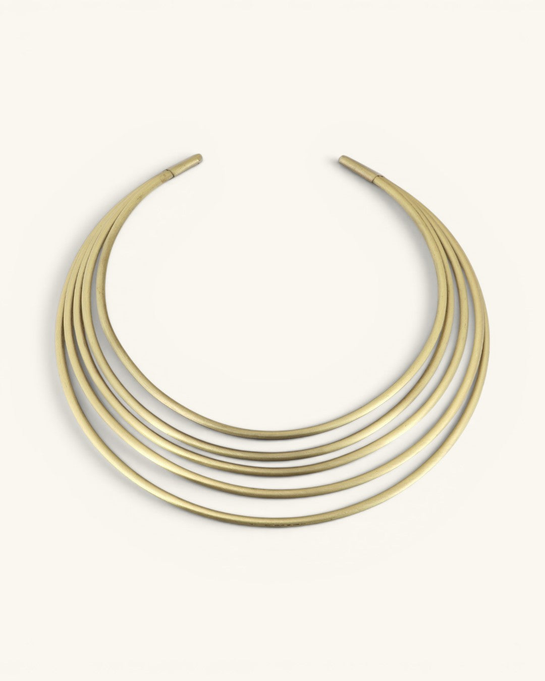 Hand-beaten brass multi-band collar necklace, front view on cream background showing five smooth curved bands