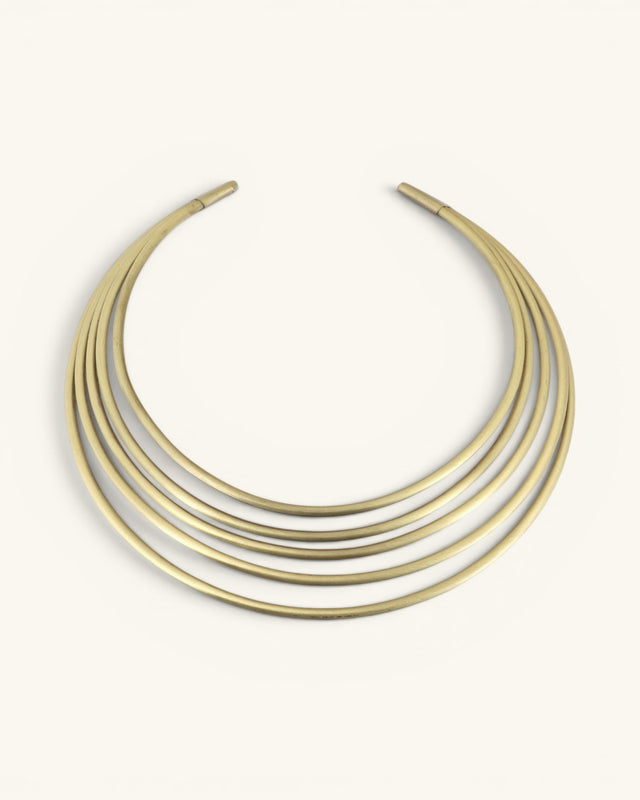 Hand-beaten brass multi-band collar necklace, front view on cream background showing five smooth curved bands