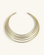 Hand-beaten brass multi-band collar necklace, front view on cream background showing five smooth curved bands