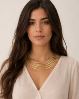 Brass five-band collar necklace worn by model in white v-neck top, front view showing fit and drape at the neckline