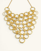 Hand-hammered brass ring bib necklace front view showing interlocked circular rings forming a V-shaped bib panel