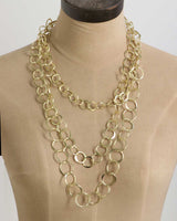 Brass three-strand hand-linked ring chain necklace on tan dress form, front view showing how three loops drape and hang