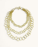 Brass hand-linked three-strand circular ring chain necklace on white background with toggle clasp at top, product front view