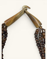 Close-up detail of the wooden bar-and-hook toggle clasp on the brown five-strand beaded necklace, unclasped