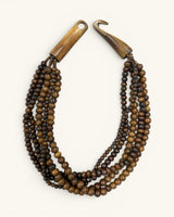 Brown five-strand beaded necklace with wooden toggle clasp unhooked and open, flat lay on cream background
