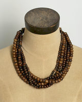 Brown five-strand beaded necklace displayed on a burlap dress form mannequin, front view showing drape and fall