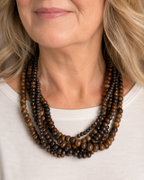 Brown five-strand beaded necklace worn by a woman in a white top, showing fit and drape at the neckline
