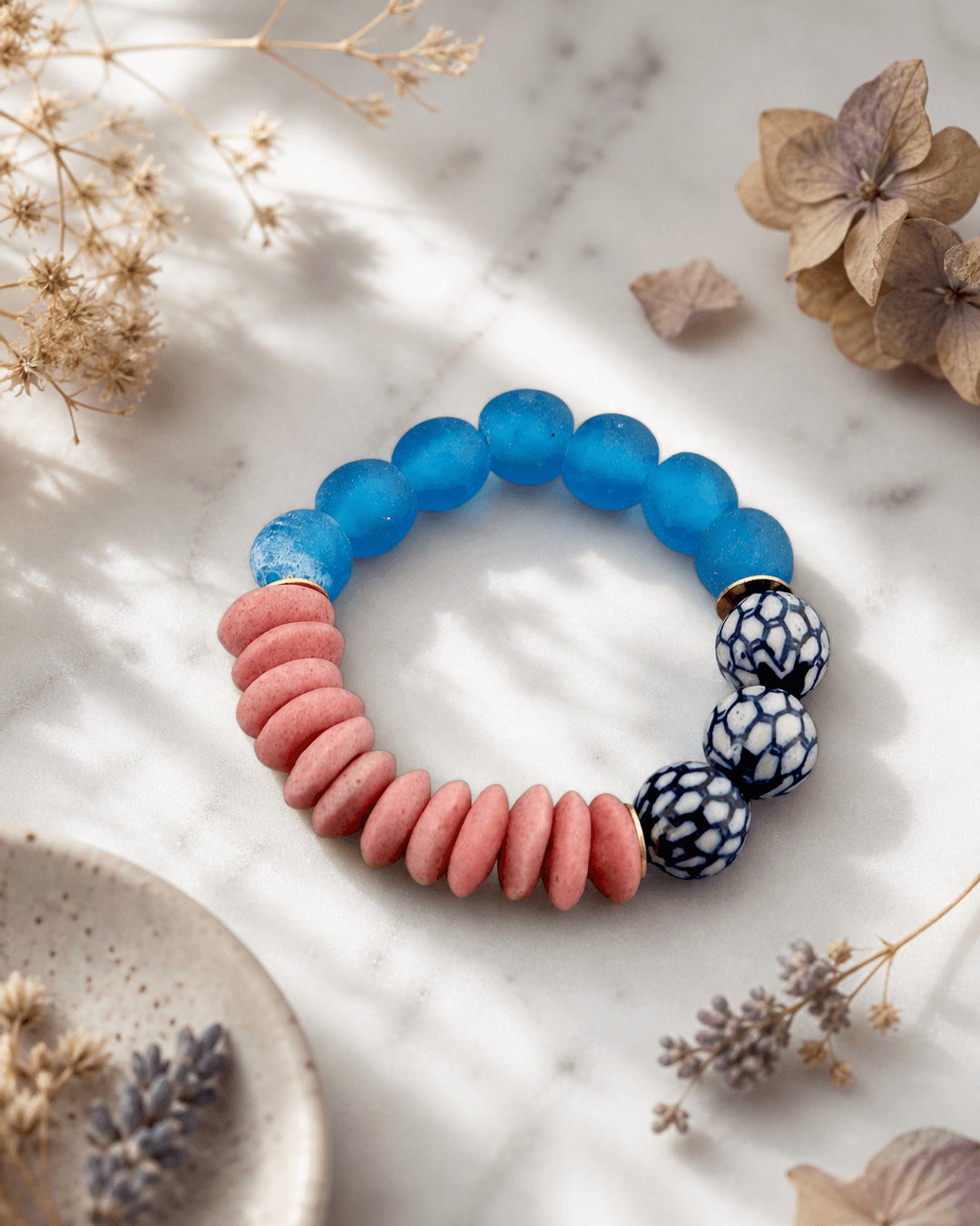 Chinoiserie stretch bracelet with colorful glass and ceramic beads displayed on white marble surface