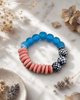 Chinoiserie stretch bracelet with colorful glass and ceramic beads displayed on white marble surface