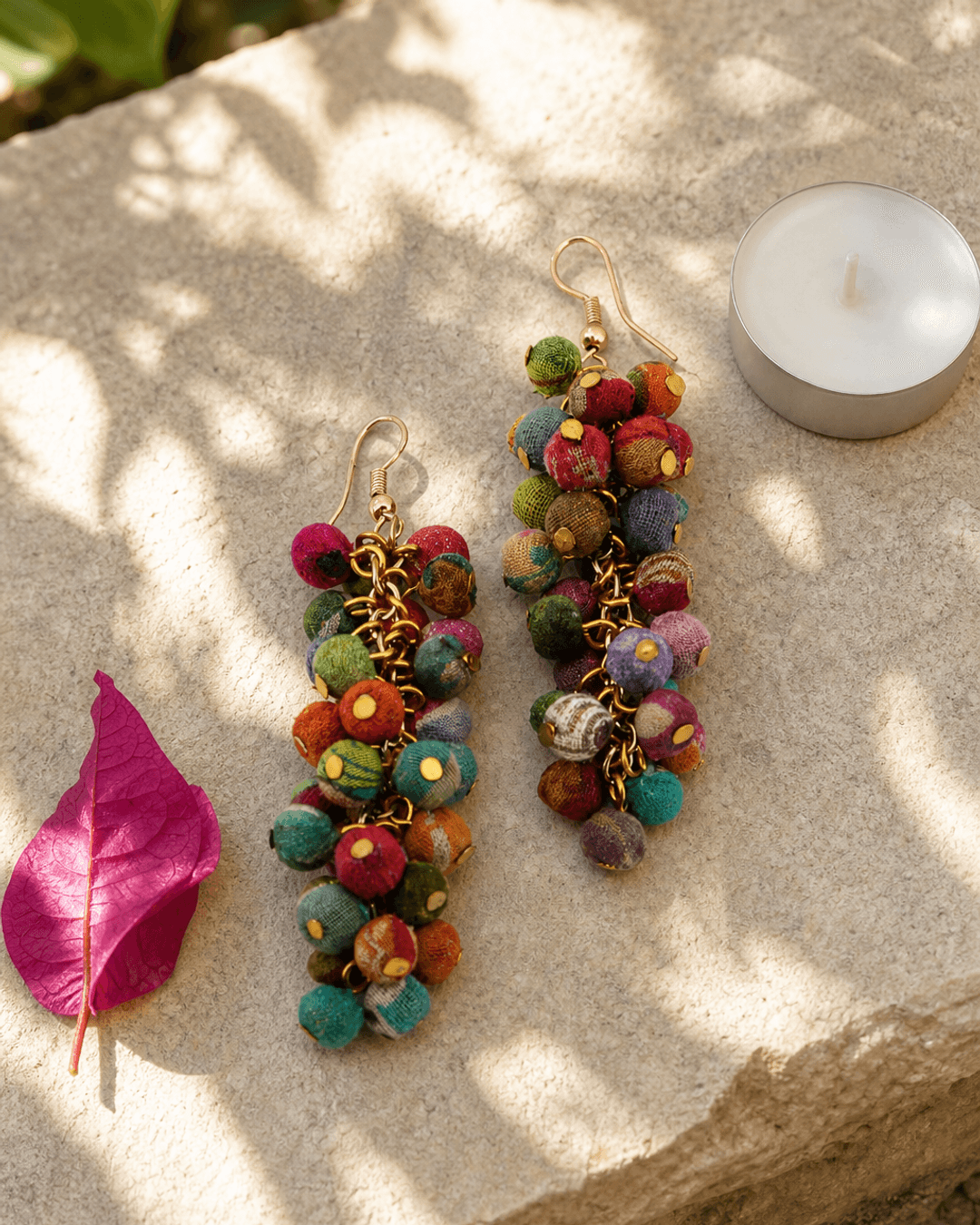 Handmade kantha cluster earrings with colorful recycled textile fabric displayed on outdoor garden stone