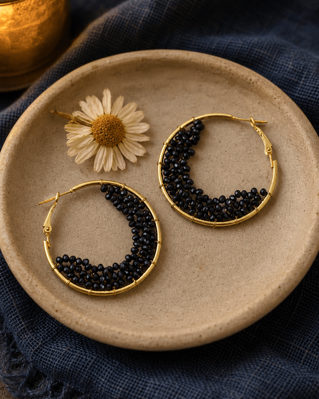 Black beaded crescent hoop earrings displayed in a serene meditation corner setting