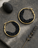 Black beaded crescent hoop earrings on a soft misty background