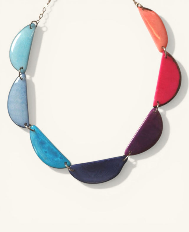 Colorful crescent-shaped Tagua necklace on beige background