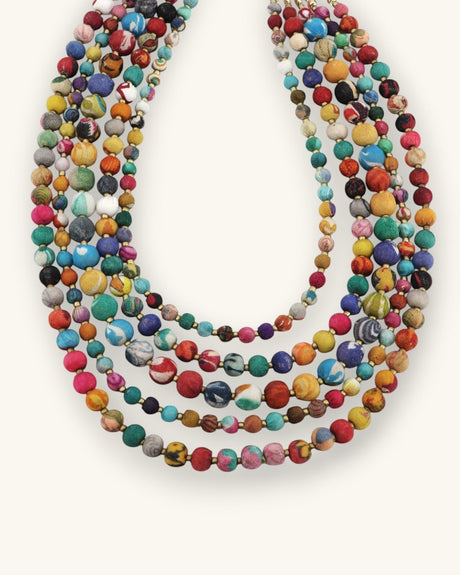 Cultural Elements multi color layered necklace with five strands of fabric beads and brass spacers.