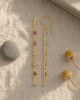 Dainty multi-color tourmaline dangle earrings displayed on a linen journal flatlay