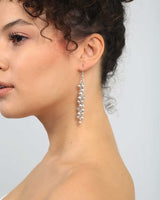 Close-up of a woman wearing silver earrings against a light background