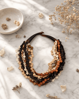 Wooden twist pendant necklace with earthy tones displayed on white marble surface