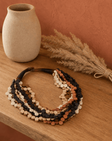 Handcrafted twist wood pendant necklace in earthy brown tones displayed on a lifestyle shelf