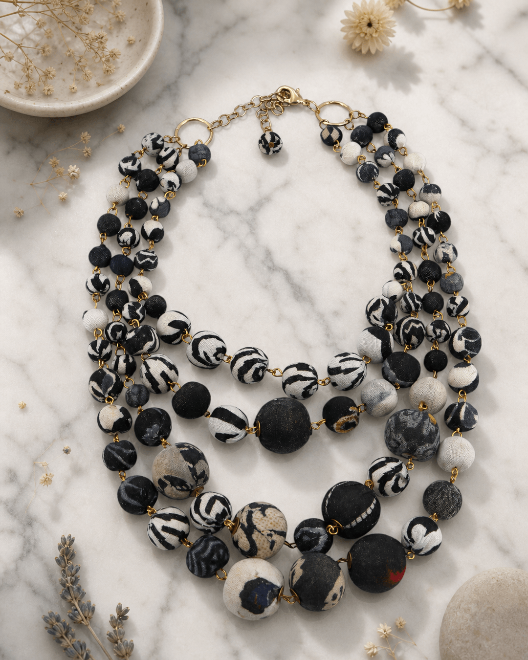 Four strand Kantha necklace with colorful fabric beads displayed on a white marble surface