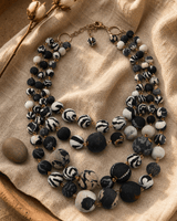 Four strand kantha necklace with colorful fabric beads displayed on a linen tray with warm rim lighting